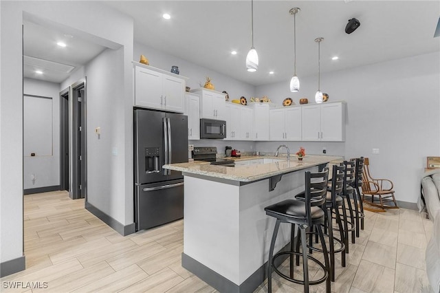 kitchen with a kitchen island with sink, black appliances, white cabinets, decorative light fixtures, and light stone counters