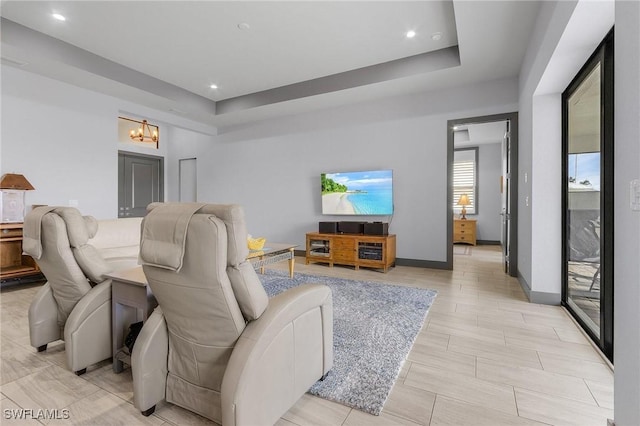 living room with a raised ceiling, light hardwood / wood-style flooring, and an inviting chandelier