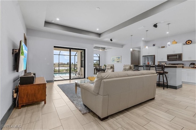 living room featuring a raised ceiling and ceiling fan