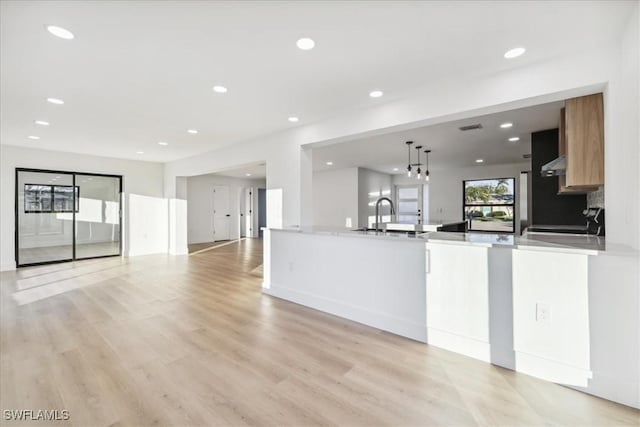 kitchen featuring pendant lighting, range, sink, and light hardwood / wood-style flooring