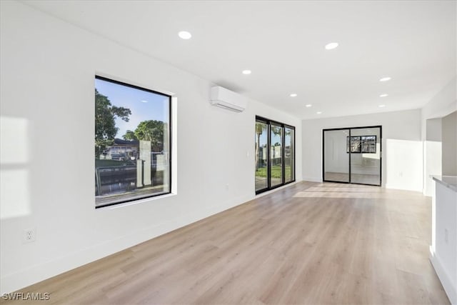 unfurnished room with a wall mounted AC and light wood-type flooring