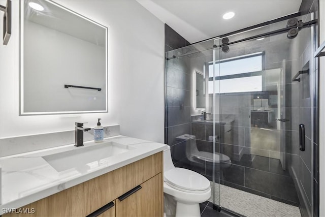 bathroom with vanity, toilet, and a shower with door