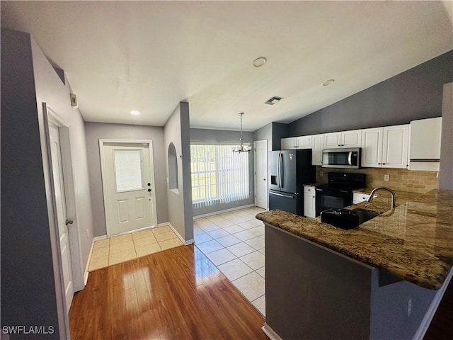 kitchen with sink, vaulted ceiling, light wood-type flooring, white cabinetry, and stainless steel appliances