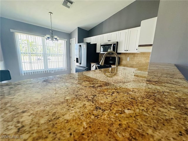 kitchen with white cabinetry, hanging light fixtures, stainless steel appliances, a chandelier, and decorative backsplash