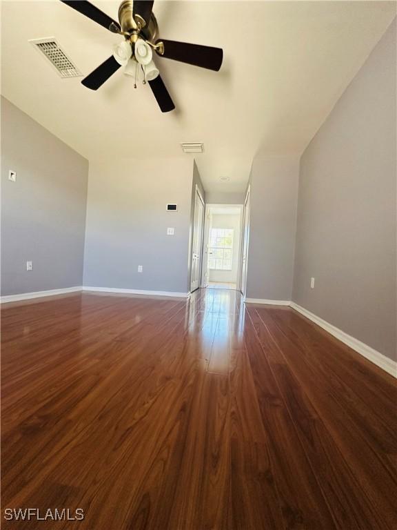 unfurnished living room featuring ceiling fan and dark wood-type flooring