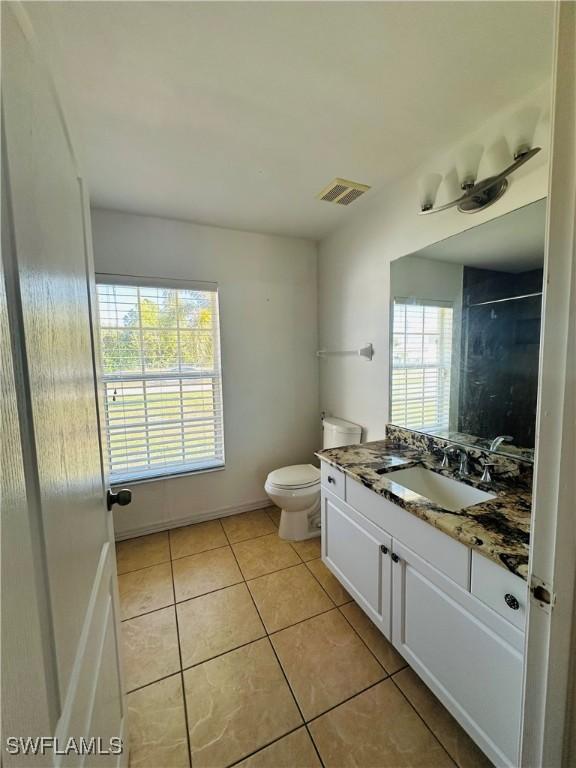 bathroom with toilet, vanity, tile patterned floors, and a healthy amount of sunlight