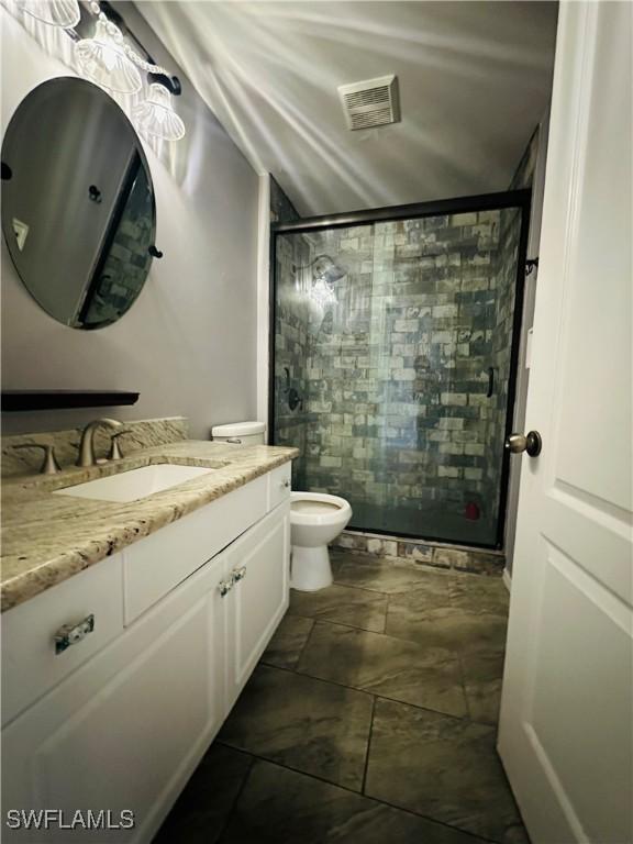 bathroom with a shower with door, vanity, and toilet