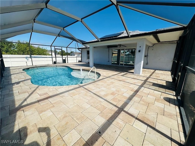 view of pool with glass enclosure, ceiling fan, and a patio area