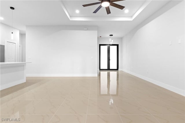 unfurnished room featuring a raised ceiling and ceiling fan