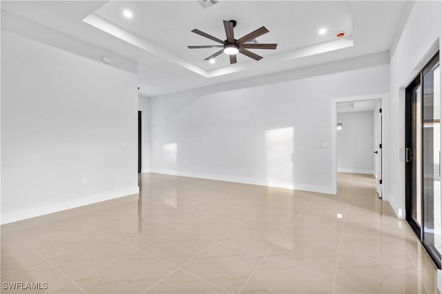 unfurnished room with ceiling fan and a tray ceiling