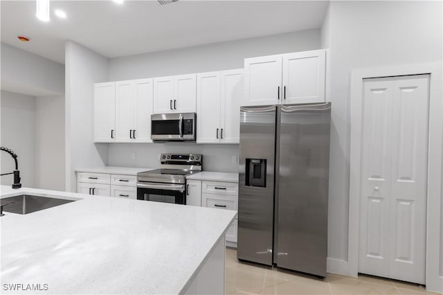 kitchen with light tile patterned flooring, sink, white cabinets, and stainless steel appliances