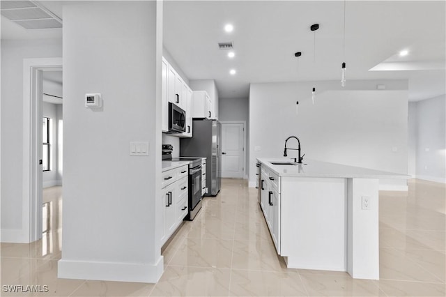 kitchen featuring sink, hanging light fixtures, stainless steel appliances, a center island with sink, and white cabinets