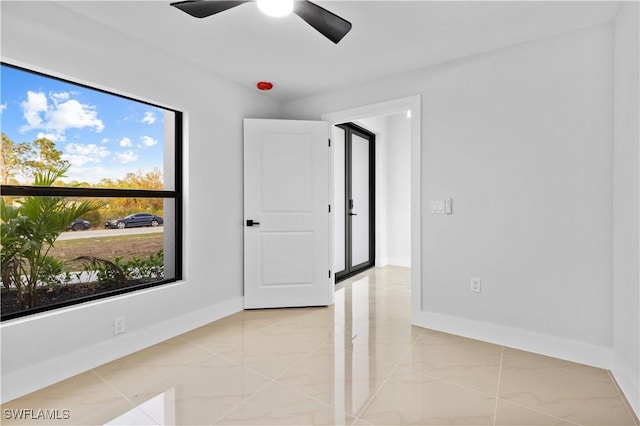 unfurnished room with ceiling fan, light tile patterned floors, and a healthy amount of sunlight