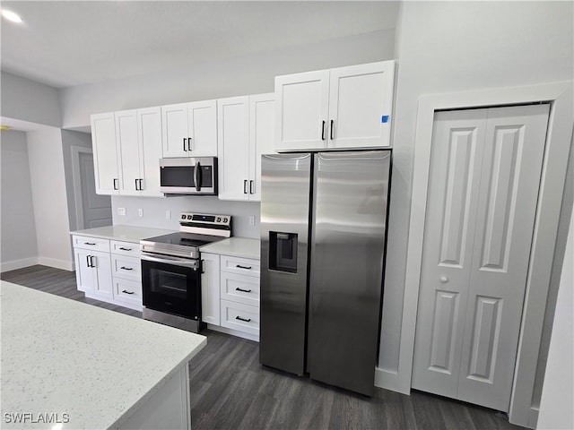 kitchen featuring stainless steel appliances, light stone counters, white cabinets, and dark hardwood / wood-style flooring