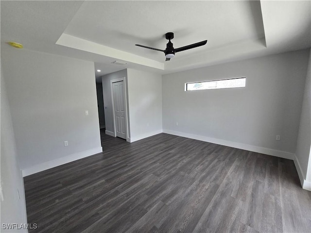 unfurnished room featuring ceiling fan, dark hardwood / wood-style flooring, and a raised ceiling