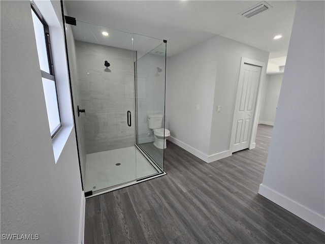 bathroom with an enclosed shower, hardwood / wood-style floors, and toilet