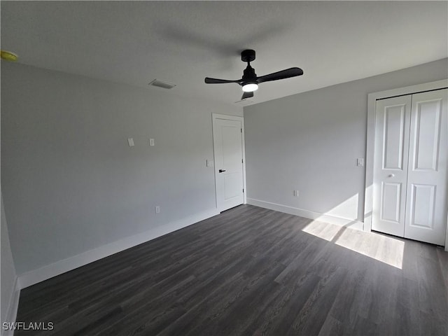 unfurnished bedroom with ceiling fan, dark hardwood / wood-style flooring, and a closet