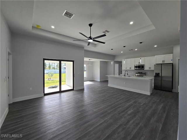 unfurnished living room featuring dark hardwood / wood-style flooring, sink, a tray ceiling, and ceiling fan