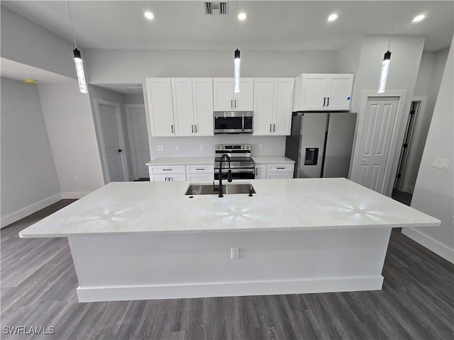 kitchen with hanging light fixtures, stainless steel appliances, and a center island with sink