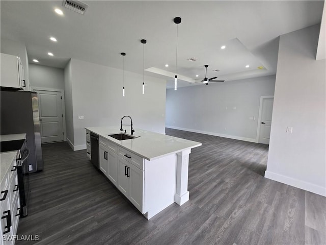 kitchen with sink, appliances with stainless steel finishes, white cabinetry, a kitchen island with sink, and hanging light fixtures