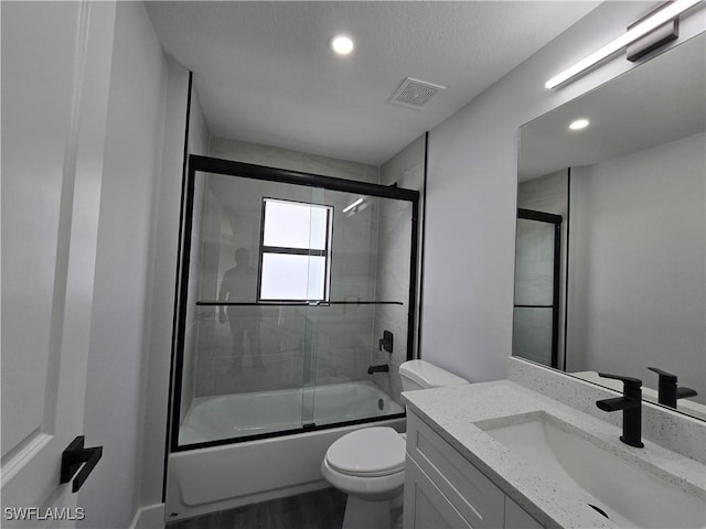 full bathroom with toilet, vanity, bath / shower combo with glass door, and hardwood / wood-style floors