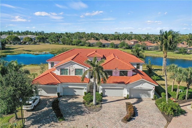 view of front of house with a tile roof, a water view, and an attached garage