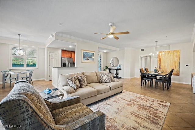 living room featuring light tile patterned floors, visible vents, baseboards, ornamental molding, and ceiling fan with notable chandelier