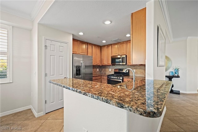 kitchen with ornamental molding, appliances with stainless steel finishes, dark stone counters, and decorative backsplash