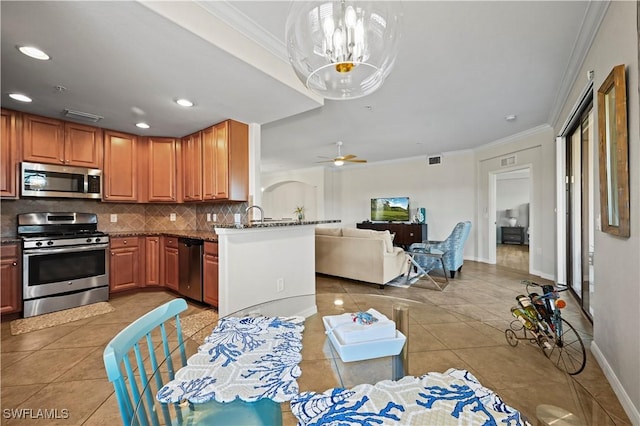 kitchen with appliances with stainless steel finishes, light tile patterned flooring, ornamental molding, and tasteful backsplash