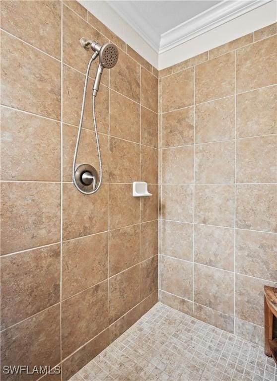 bathroom with ornamental molding and tiled shower