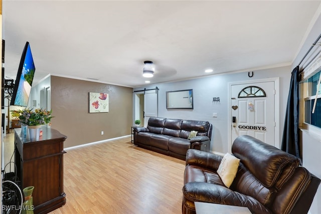 living room with a barn door, crown molding, and light hardwood / wood-style flooring