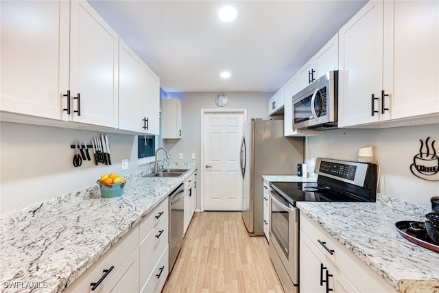 kitchen featuring white cabinets, appliances with stainless steel finishes, light wood-type flooring, and sink