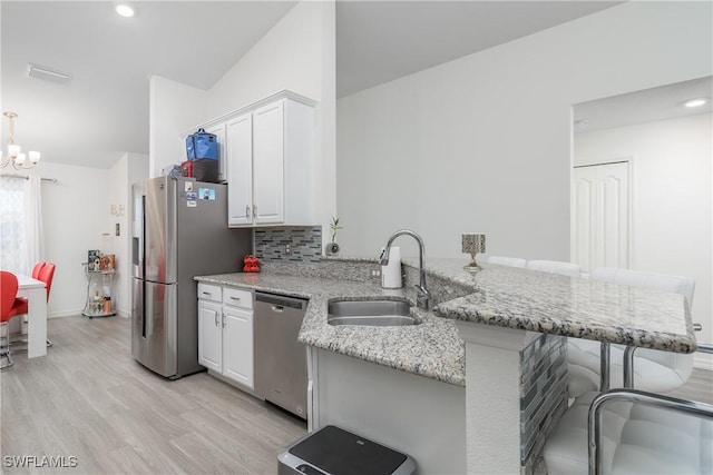 kitchen featuring white cabinets, a kitchen breakfast bar, sink, kitchen peninsula, and stainless steel appliances