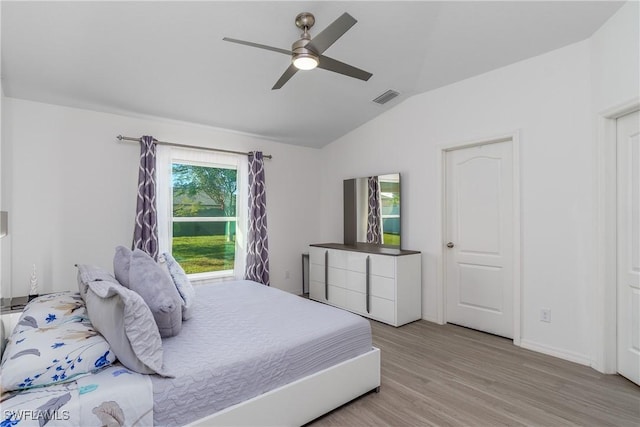 bedroom with light hardwood / wood-style floors, vaulted ceiling, and ceiling fan