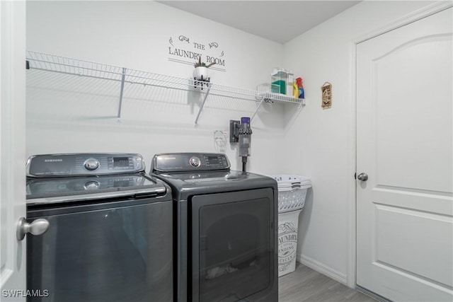 clothes washing area featuring washer and clothes dryer and light hardwood / wood-style flooring