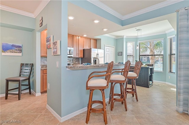 kitchen with backsplash, light stone countertops, stainless steel appliances, and a kitchen bar