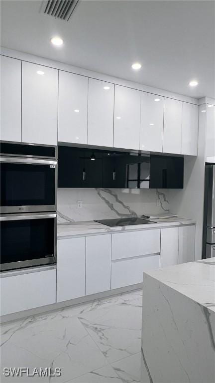 kitchen with tasteful backsplash, light stone countertops, white cabinets, and stainless steel appliances