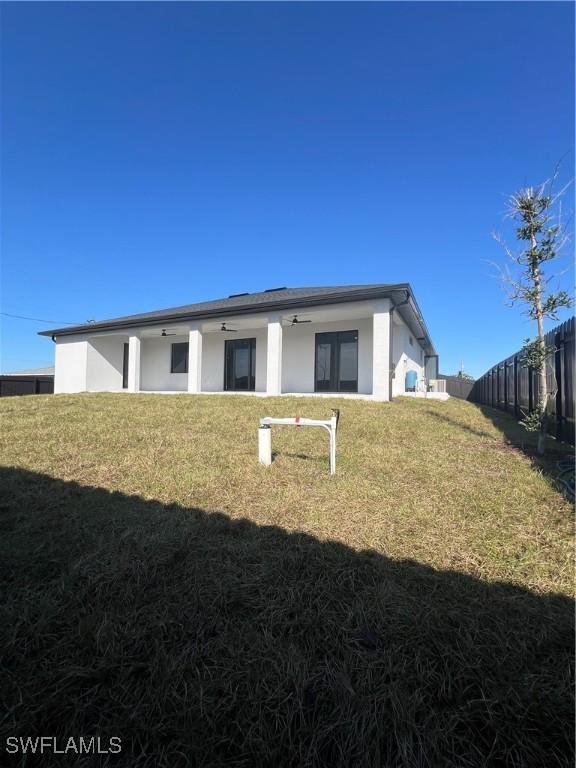 back of house featuring a yard and ceiling fan