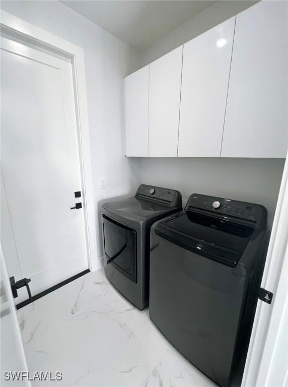 clothes washing area with washing machine and clothes dryer and cabinets