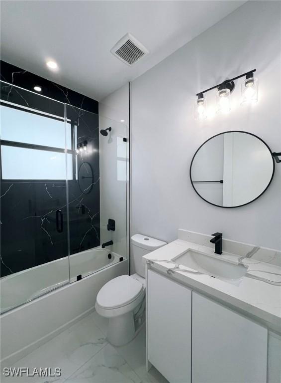 full bathroom featuring vanity, bath / shower combo with glass door, and toilet