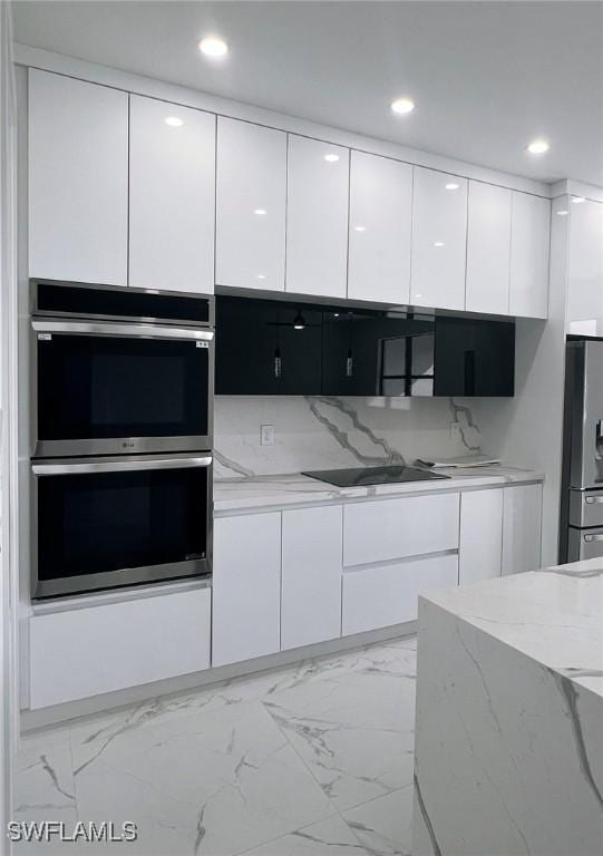 kitchen with white cabinets, appliances with stainless steel finishes, backsplash, and light stone countertops