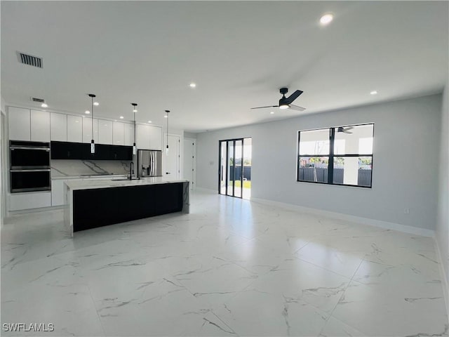 kitchen featuring stainless steel refrigerator with ice dispenser, backsplash, a large island with sink, white cabinets, and hanging light fixtures