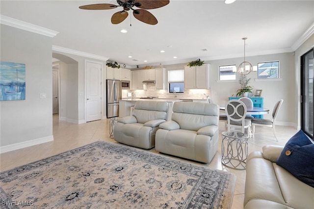 tiled living room featuring ceiling fan with notable chandelier and crown molding