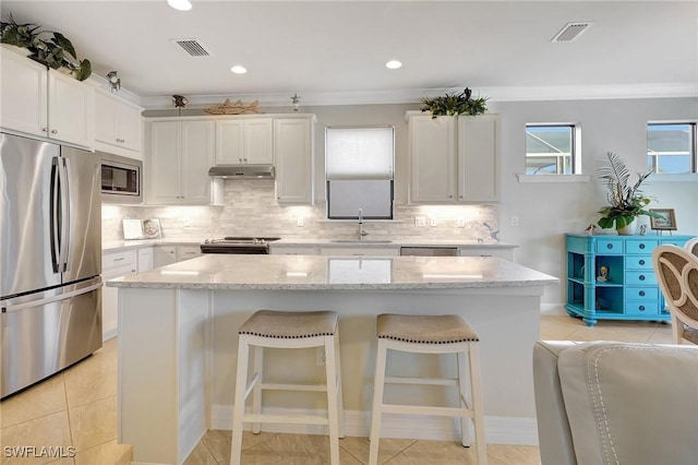 kitchen with white cabinets, a kitchen island, sink, and appliances with stainless steel finishes