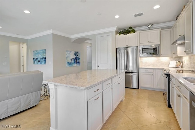 kitchen with light stone countertops, stainless steel appliances, crown molding, white cabinets, and a center island