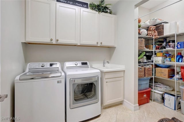 clothes washing area featuring cabinets, light tile patterned floors, washing machine and dryer, and sink