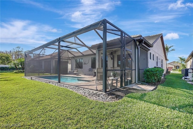 rear view of property featuring a lawn, glass enclosure, and a patio area