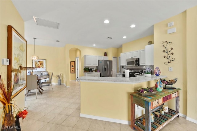 kitchen featuring backsplash, kitchen peninsula, appliances with stainless steel finishes, decorative light fixtures, and white cabinetry