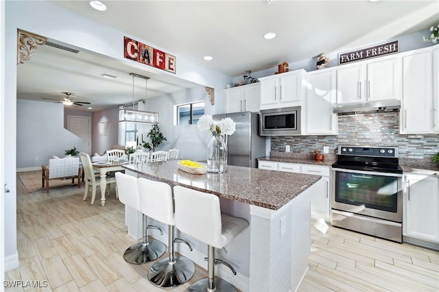 kitchen featuring white cabinetry, ceiling fan, pendant lighting, a kitchen island, and appliances with stainless steel finishes