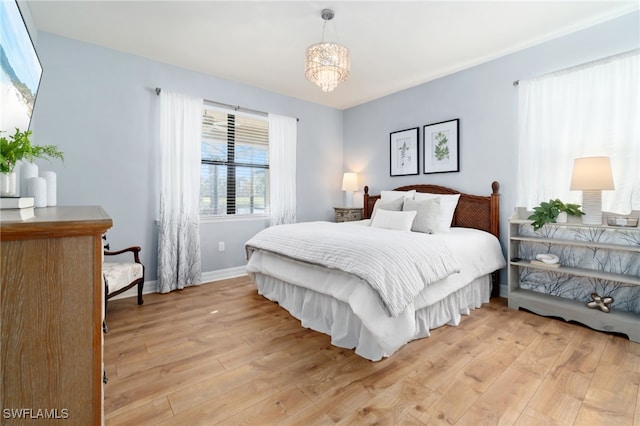 bedroom with light wood-type flooring and a notable chandelier